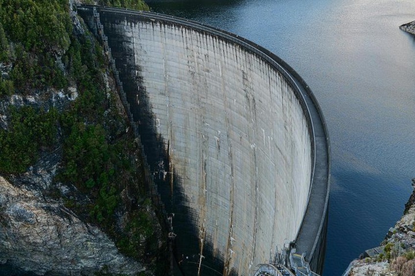 Una gran presa con estructura curva, rodeada de agua y vegetación. 1