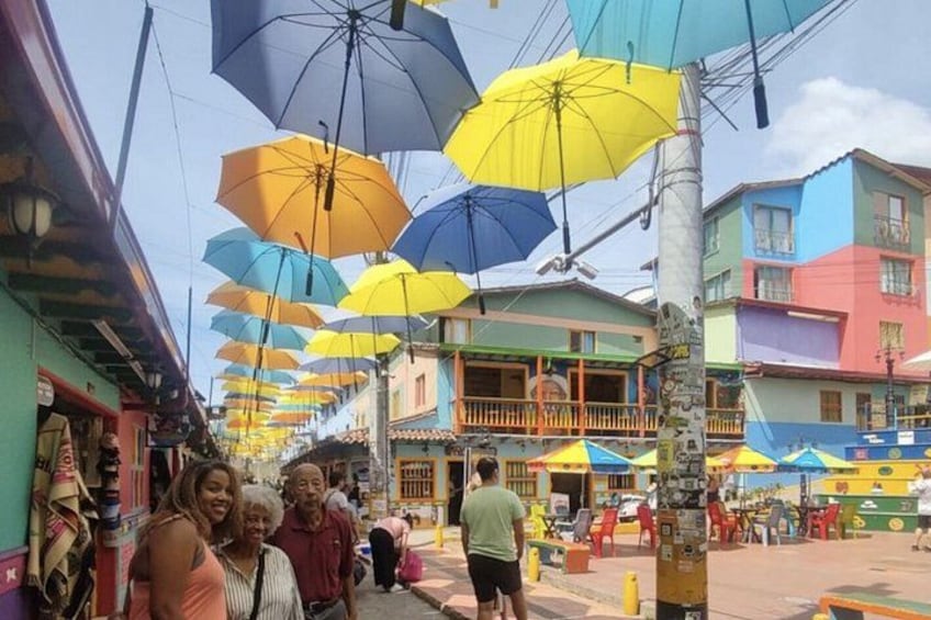 Une rue bordée de parasols colorés, de bâtiments et de passants. 1