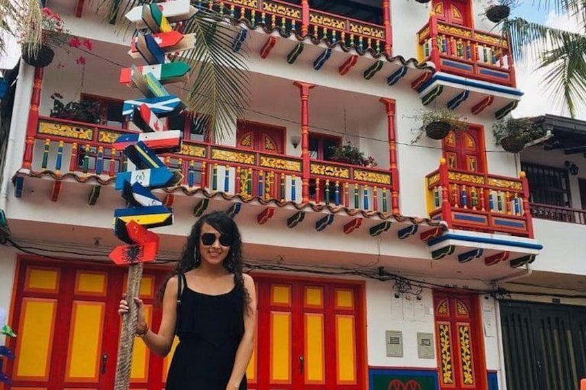 Une personne se tient devant un bâtiment coloré, orné de balcons et de drapeaux. 5