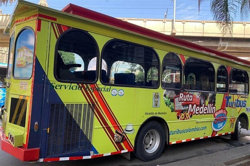 Un autobus aux couleurs vives, orné de publicités pour Ruta Medellín et Tribus. 2