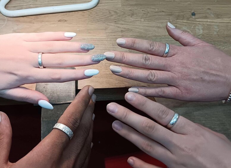 Multiple hands with manicured nails, some with glitter and others with a matte finish, and various rings on the fingers. 4