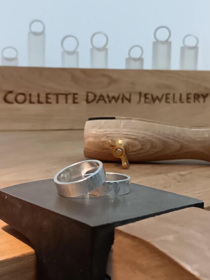 A metal ring on a black stand with a wooden background labeled 'Collette Dawn Jewellery.' 2