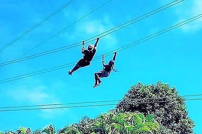 Two people bungee jumping with a clear blue sky and power lines in the background. 2