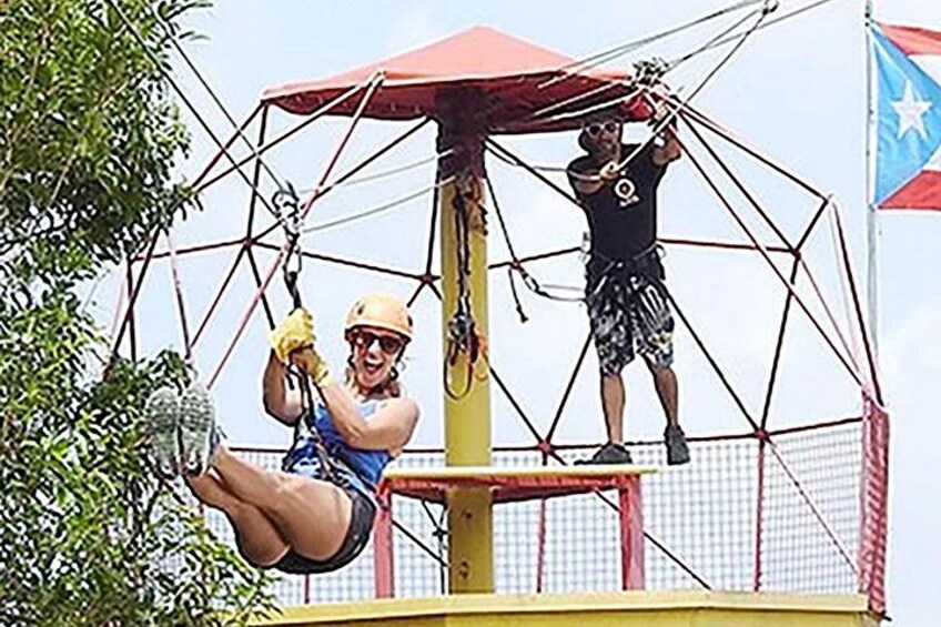 A person swinging on a rope, another person assisting, and a flag in the background. 3