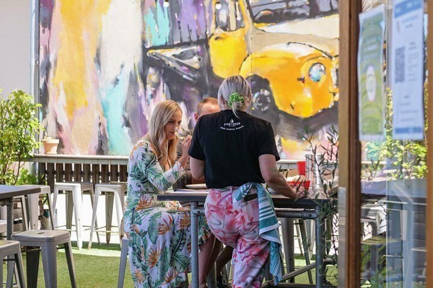 Un área de comedor al aire libre con una amplia pintura abstracta al fondo. 2