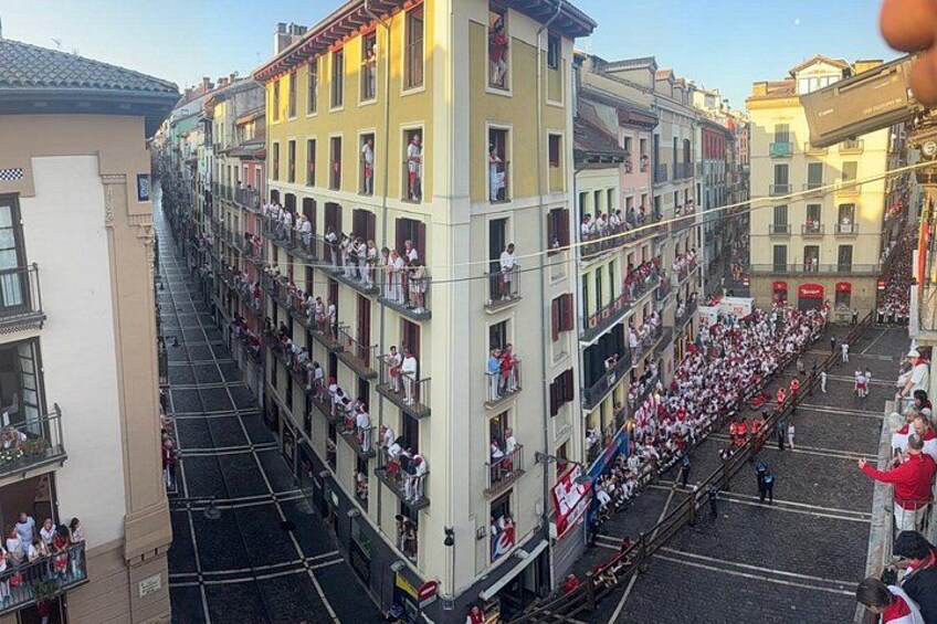 Une rue animée, avec des gens sur les balcons et un immeuble à plusieurs étages. 1