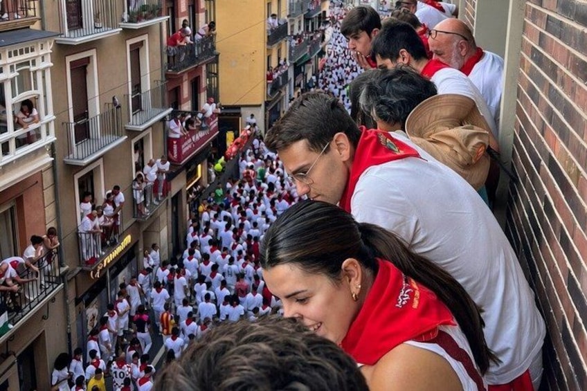 Une rue bondée, où l’on voit des gens portant des chemises blanches et des écharpes rouges, participant probablement à une procession ou à un événement. 3