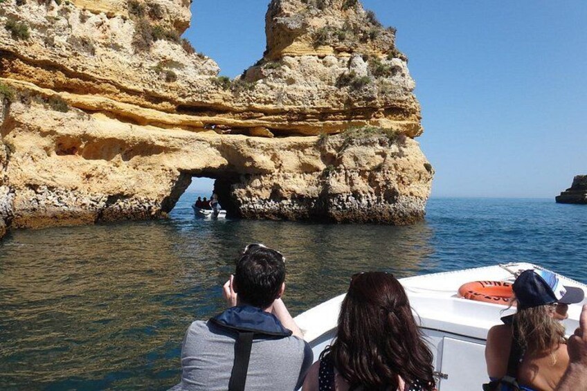 A boat navigating through a rocky coastal area with a large rock formation and a natural archway. 2