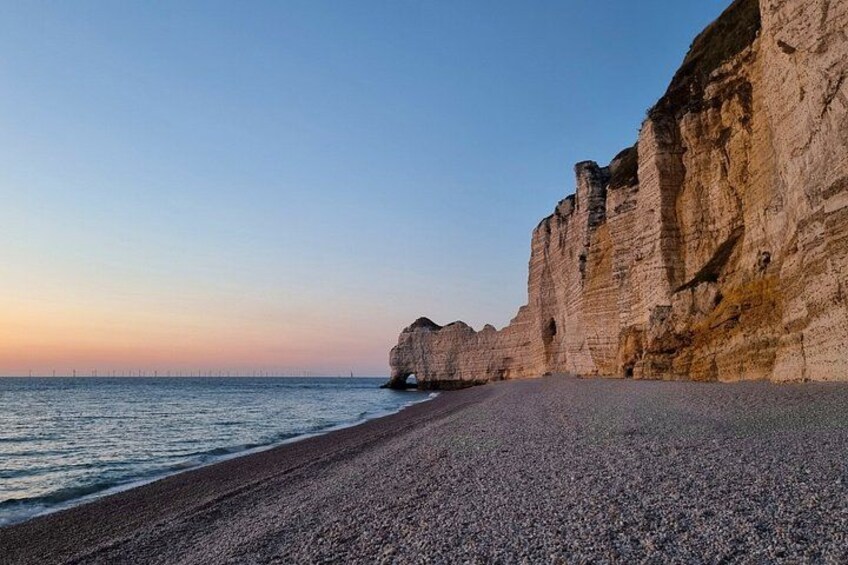 Ein Kiesstrand mit Klippen und blauem Himmel. 2