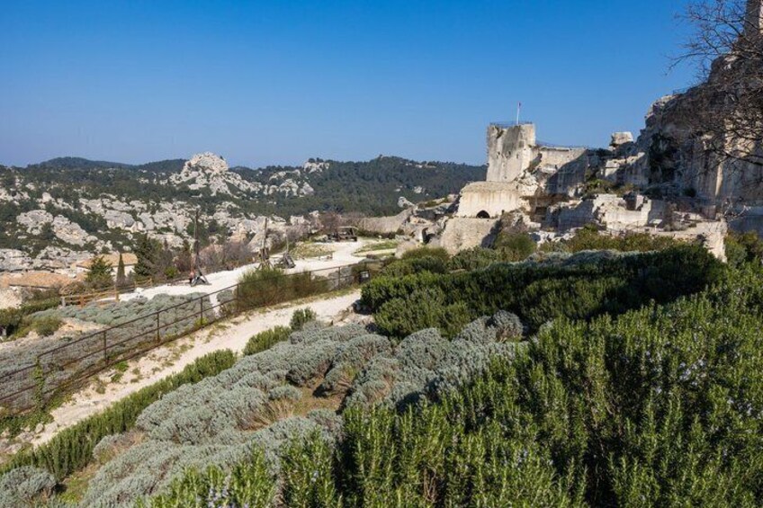 Un paisaje rocoso con un edificio histórico, abundante vegetación y un cielo despejado. 4