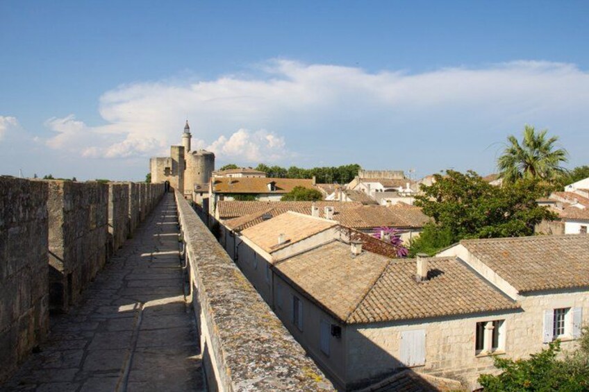 A stone pathway leading to a historic building with a tower, surrounded by traditional houses with tiled roofs. 4
