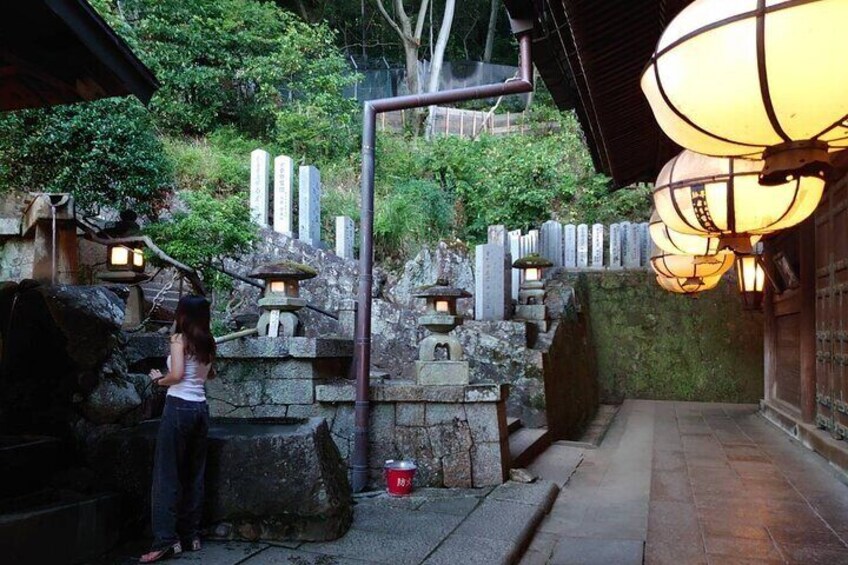 A traditional Japanese garden with stone lanterns, a stone pathway, and a person standing by a stone basin. 3