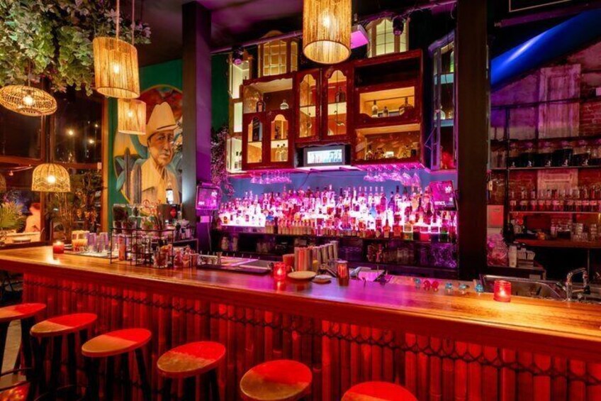 A bar with red stools, a bar counter, and a mural. 4