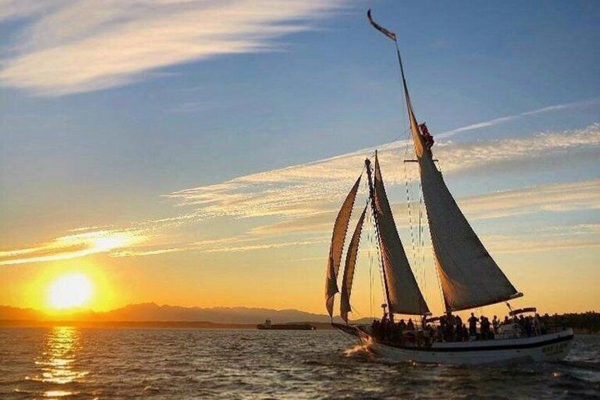 Un voilier avec plusieurs voiles naviguant sur une étendue d’eau au coucher du soleil. 3