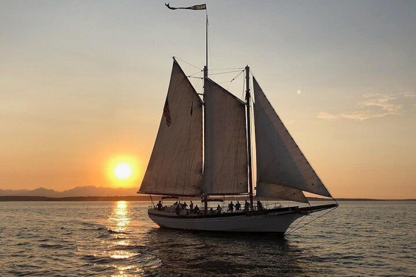 Ein Segelboot mit mehreren Segeln auf ruhigem Wasser bei Sonnenuntergang. 2