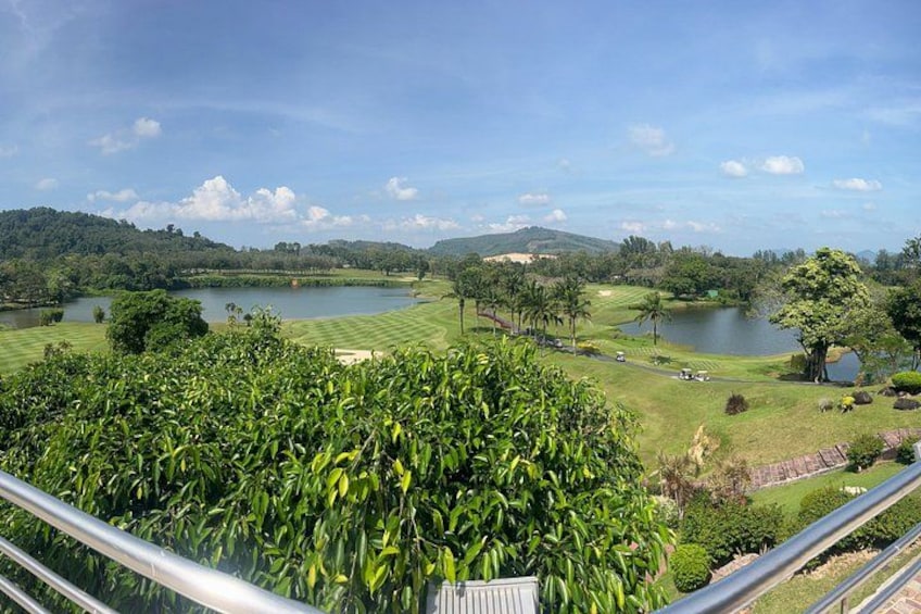 A golf course with a lake, trees, and hills in the background. 2