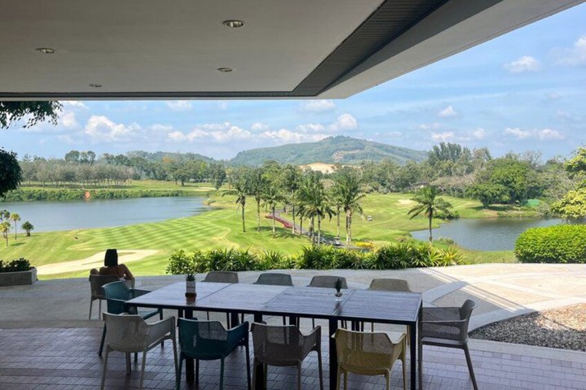 A patio with a table and chairs overlooking a golf course and lake. 4