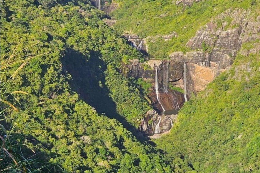 Un exuberante valle verde con cascadas que descienden por un acantilado rocoso. 1