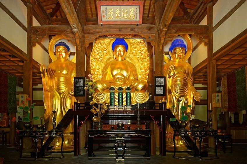 A temple interior with golden Buddha statues and traditional Japanese architecture. 5