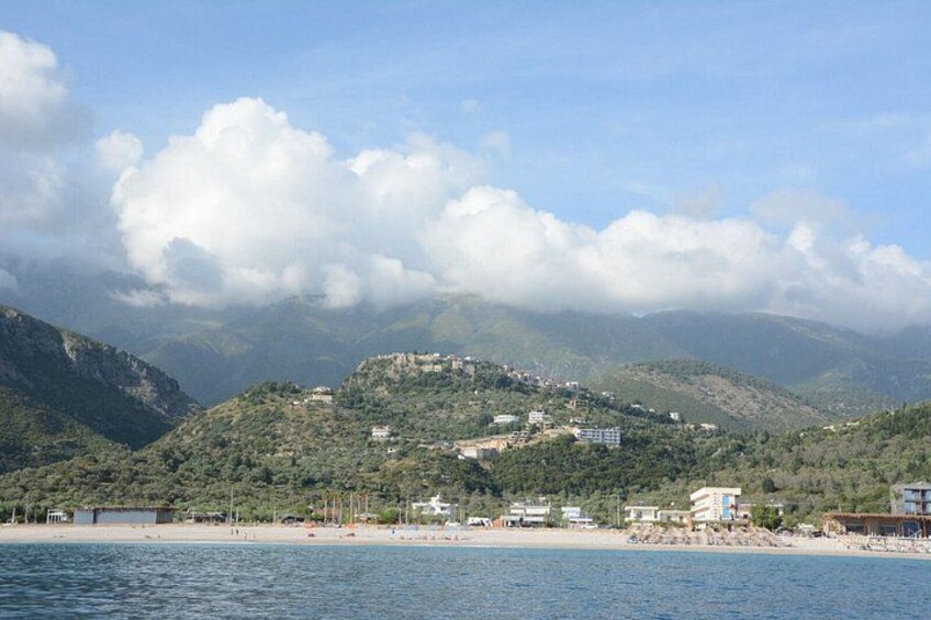 Un paisaje costero con montaña, playa y edificios. 2