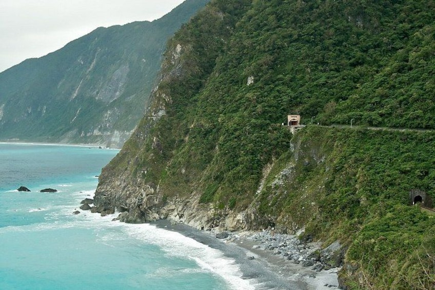 A coastal landscape with a road winding along a cliffside, overlooking the ocean. 5