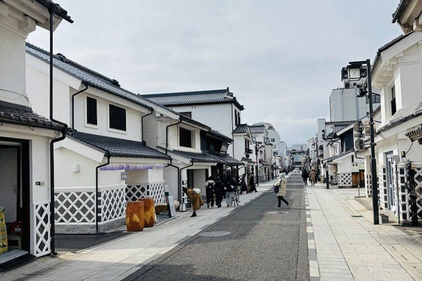 A narrow street lined with traditional buildings, a few pedestrians, and a clear sky. 4