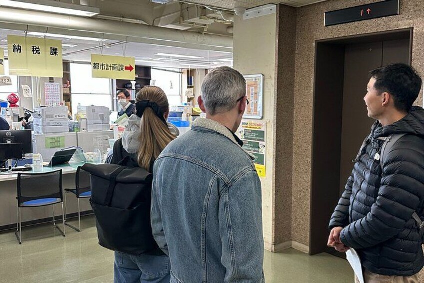 A public space with people standing and interacting, signs with Japanese text, and a door. 5