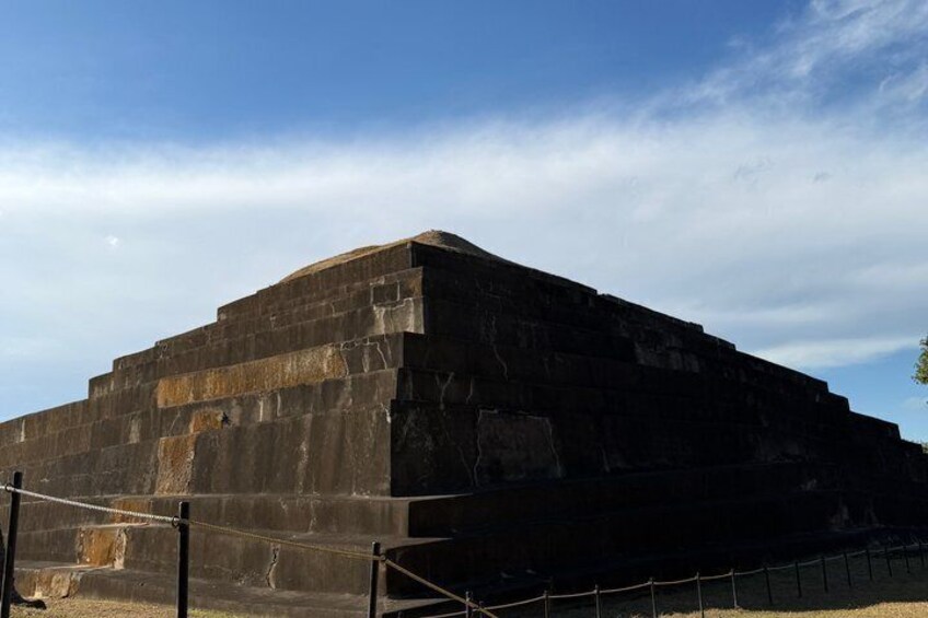 A large, dark stone structure with a flat top, surrounded by a fence. 4
