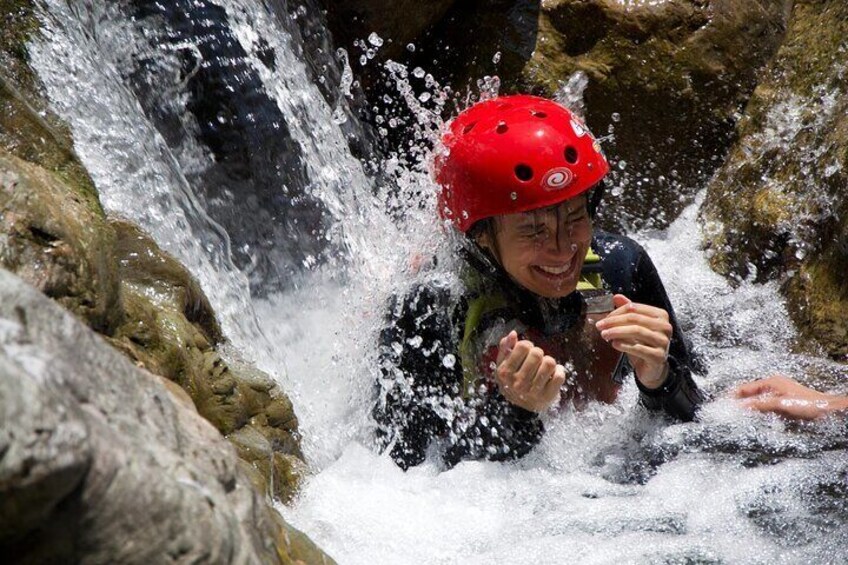 Eine Person mit rotem Helm und Neoprenanzug steuert einen reißenden Fluss. 1