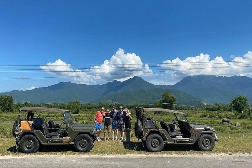 Two off-road vehicles parked on a road with a mountainous landscape in the background. 1