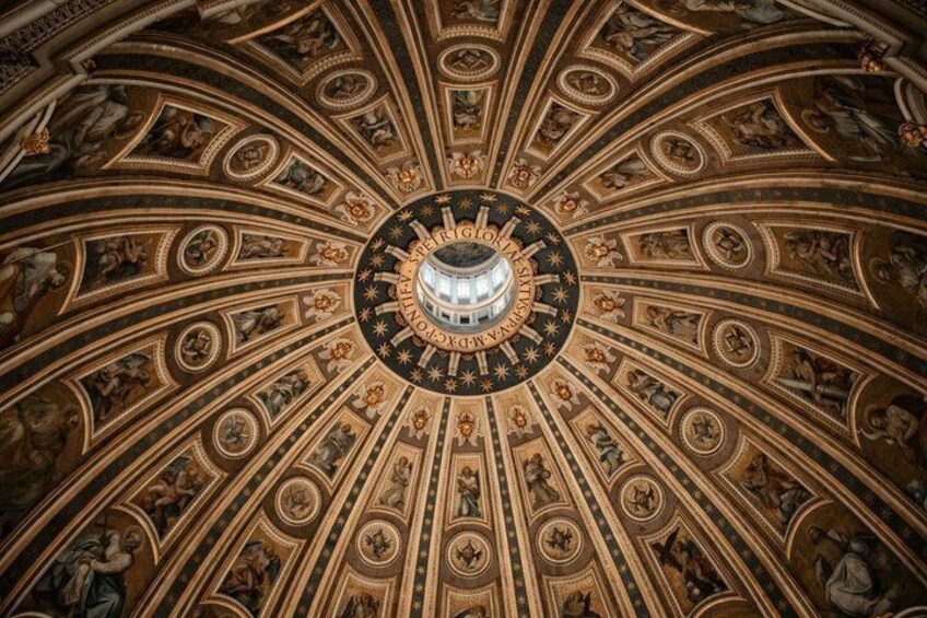 A detailed ceiling with a central circular design and surrounding frescoes. 5