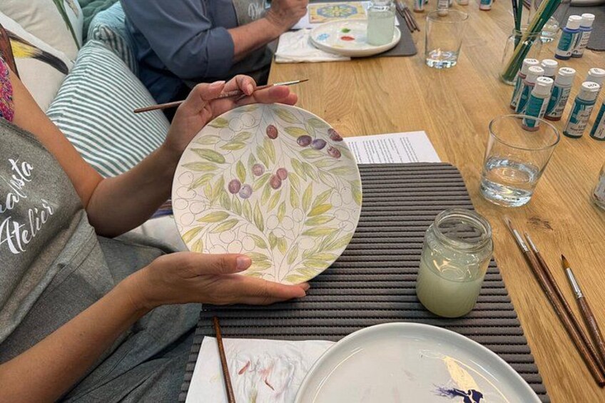 A person painting a plate with a floral design. 3