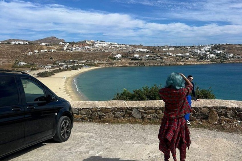Une route côtière avec une voiture garée sur le bord, une personne prenant une photo et une plage en arrière-plan. 2