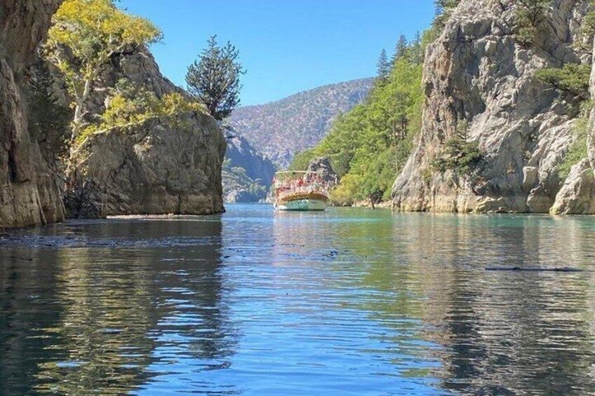 A river with a boat, rocky cliffs, and trees. 2