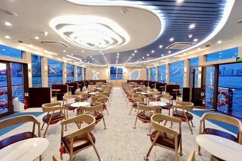 A modern dining area with rows of chairs and tables, large windows with a view of the city, and a circular ceiling design. 4