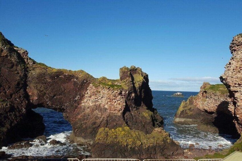 A coastal landscape with prominent rock formations and a clear blue sky. 2