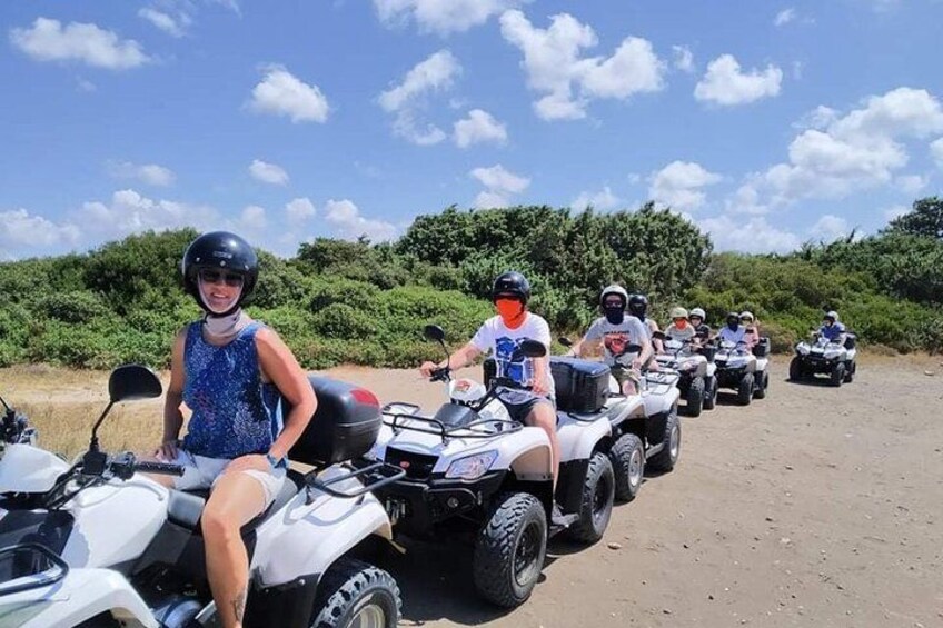A group of people riding ATVs on a dirt road with greenery in the background. 2