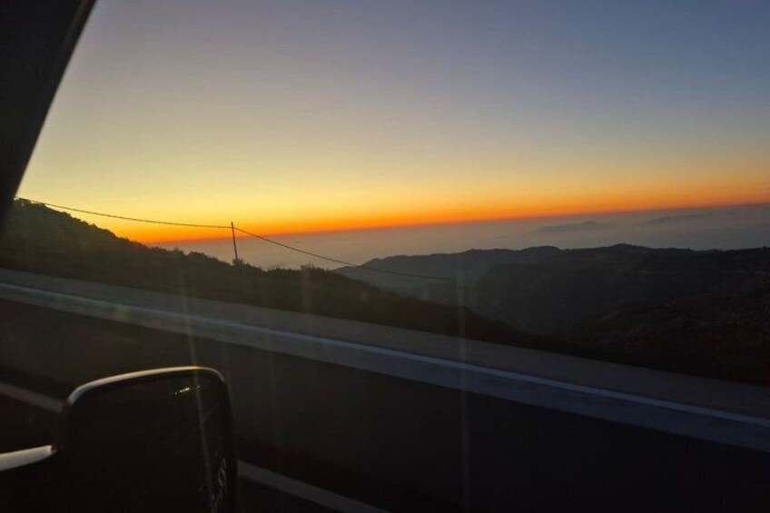 A sunset over a mountainous landscape with a road in the foreground. 5