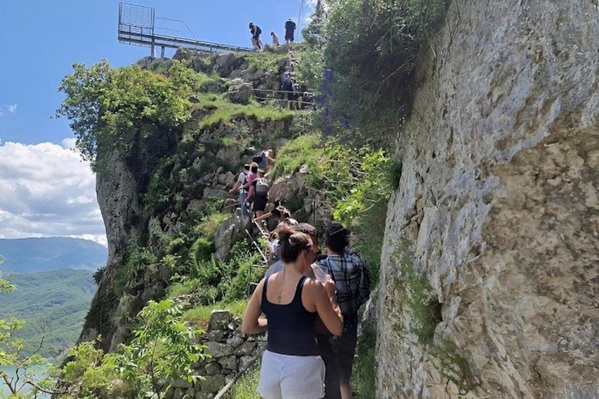 A group of people hiking on a rocky cliff with a view of the landscape below. 2