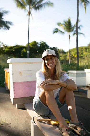 A person sitting on a wooden platform with a beehive in the background. 3