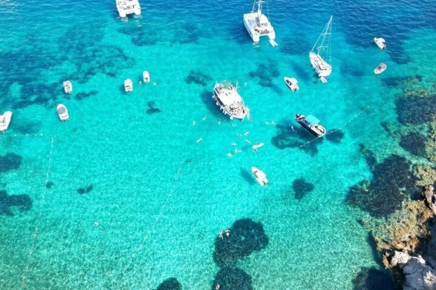 Mare turchese con imbarcazioni ancorate lungo un litorale roccioso. 1