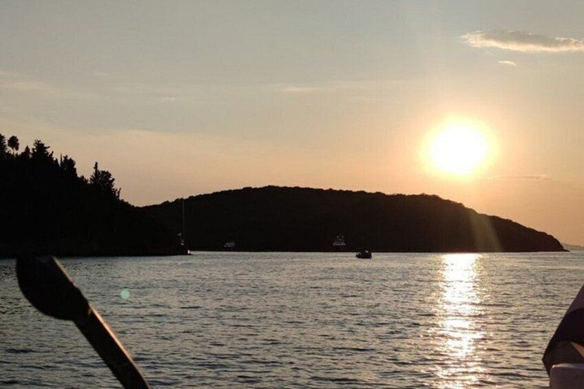 A sunset over a body of water with a boat and a small island in the distance. 1