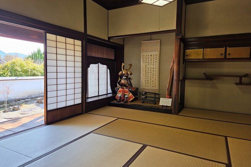 A traditional Japanese room with tatami flooring, sliding doors, and a decorative figure. 2