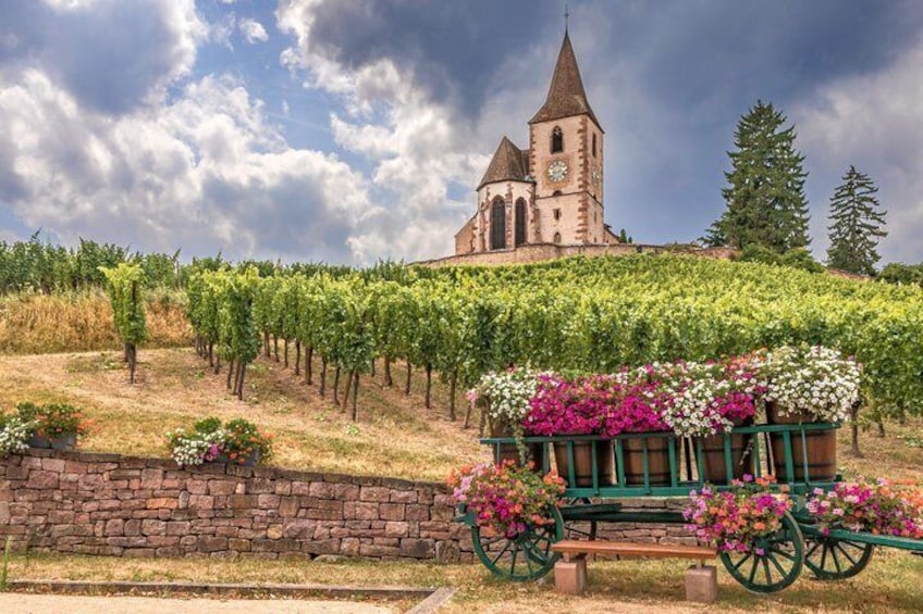 A vineyard, a stone wall, a church with a tower, and a flower cart. 2