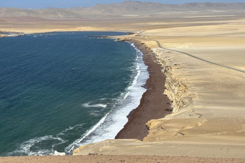 A coastal landscape with a sandy beach, ocean waves, and distant mountains. 2