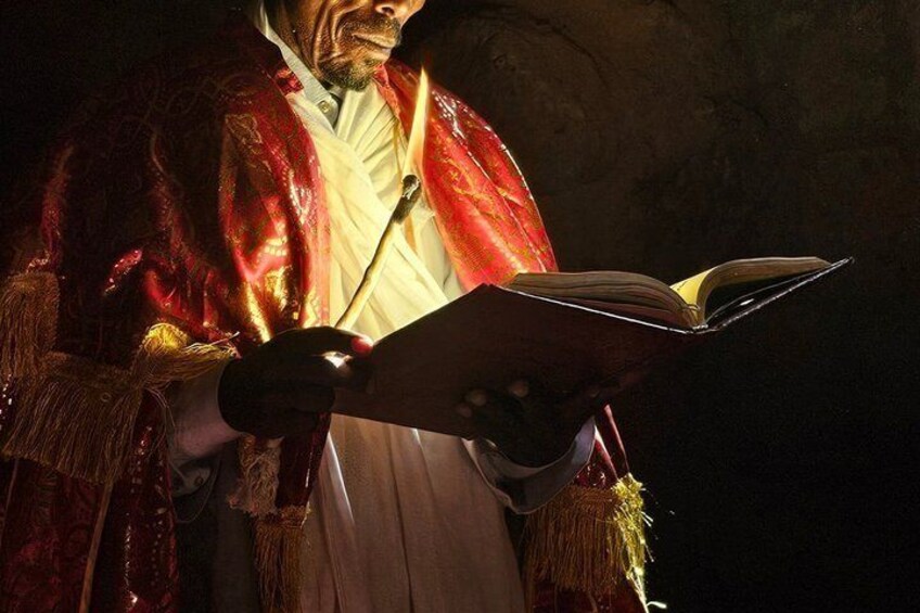 A person in a red robe holding an open book. 1