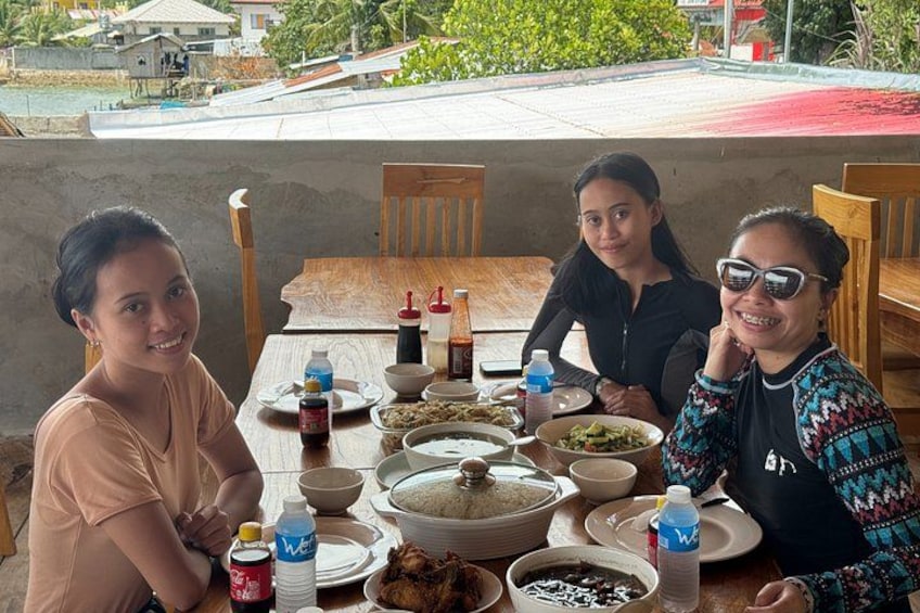 Three people sitting at a table with various dishes and condiments. 2