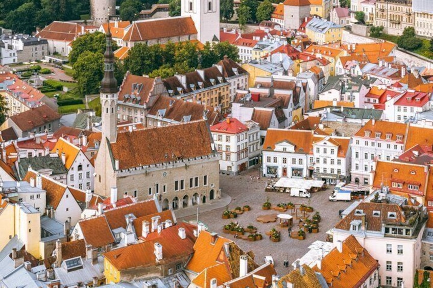 A historic town square with red-roofed buildings, a prominent church tower, and a central open space. 4