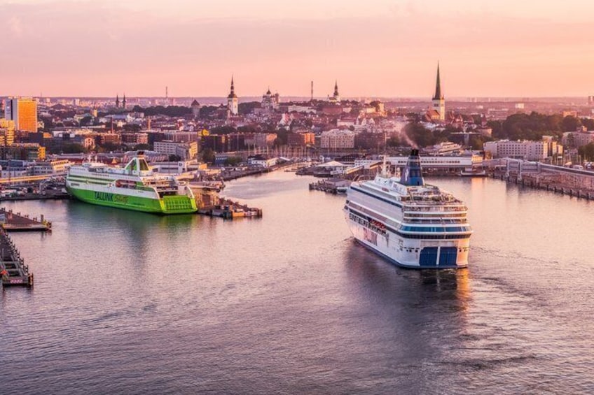 Two cruise ships docked at a port with a cityscape in the background. 1