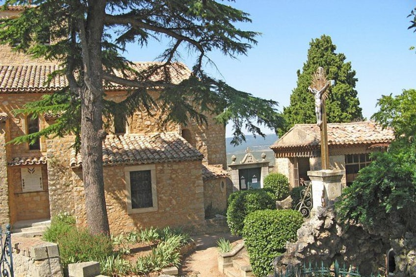 Un edificio de piedra con techo de tejas, una estatua y un árbol. 1